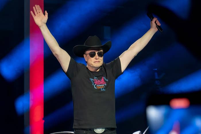 Elon wearing a cowboy hat and sunglasses on a stage