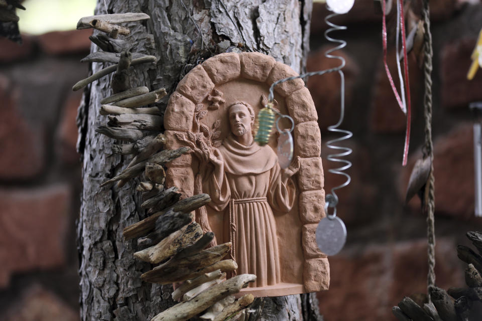 An image of St. Francis of Assisi, patron saint of animals, hangs from a tree at the Selah Carefarm in Cornville, Ariz., Oct. 4, 2022. Across the farm, stories repeat of someone washed over by a wave of grief only to find an animal seem to offer comfort – a donkey nestling its face in a crying woman’s shoulder or a horse pressing its head against a grieving heart. (AP Photo/Dario Lopez-Mills)