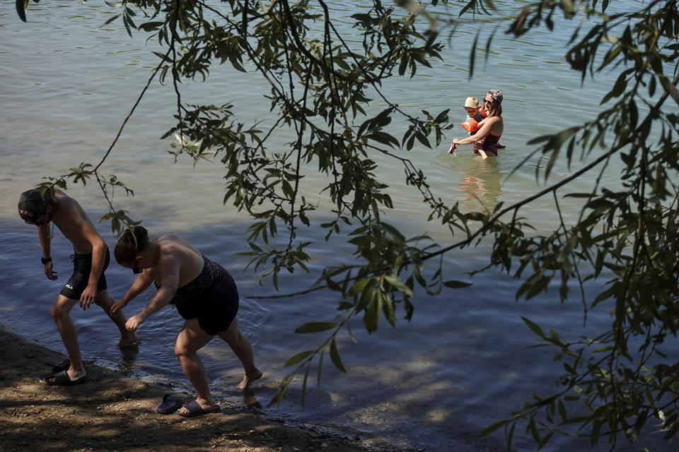 A woman enjoys the water with her son during a heatwave in Anse, outside Lyon, central France, Sunday, July 17, 2022. (AP Photo/Laurent Cipriani)