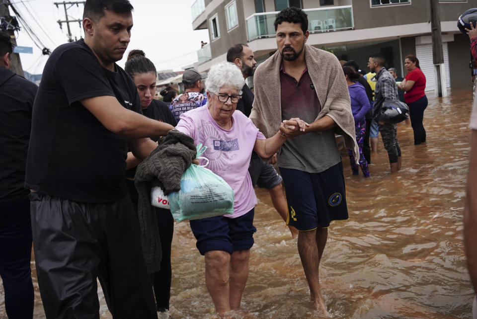 Residents evacuate from a neighborhood flooded by heavy rains, in Canoas, Rio Grande do Sul state, Brazil, Saturday, May 4, 2024. (AP Photo/Carlos Macedo)