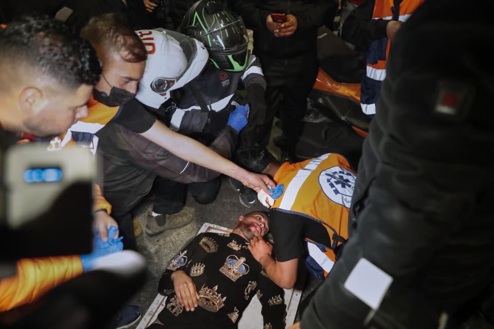 A wounded Palestinian demonstrator receives treatment after he was hit during clashes with Israeli police at Damascus Gate just outside Jerusalem's Old City, Thursday, April 22, 2021. Palestinians clash with Israeli police over restrictions on Ramadan gatherings ahead of a planned march by Lahava, a Jewish extremist group, to the area later on Thursday amid heightened tensions in the city. (AP Photo/Ariel Schalit)