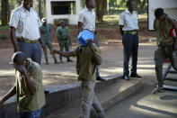 Street currency dealers cover their faces while making a court appearance at the magistrates courts in Harare, Zimbabwe, Thursday, April 25, 2024. Authorities in Zimbabwe are resorting to force to defend the new currency, including packing jail cells with dozens of street currency dealers and freezing accounts of hordes of businesses accused of undermining the value of the ZiG. (AP Photo/Tsvangirayi Mukwazhi)