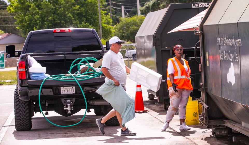 Tamika Lewis, a recycling attendant, right, watches as Joey Belle throws pillows and styrofoam in a trash compactor as people were dropping off household garbage and recyclables at the Baseline Recycling Center on May 13.