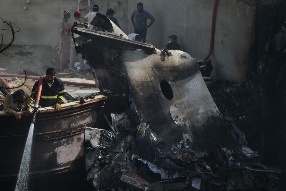 A firefighter sprays water on the wreckage of a Pakistan International Airlines aircraft after it crashed in a residential area in Karachi on May 22, 2020. - A Pakistani plane with nearly 100 people on board crashed into a residential area in the southern city of Karachi on May 22, killing several people on the ground. (Photo by Rizwan TABASSUM / AFP) (Photo by RIZWAN TABASSUM/AFP via Getty Images)