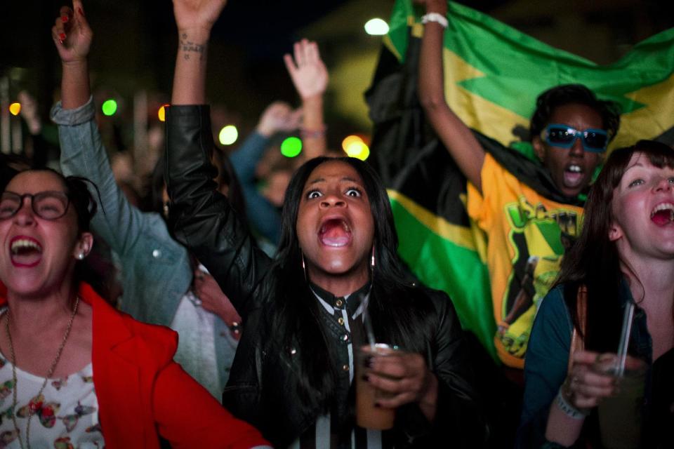 In this Sunday, Aug. 5, 2012 photo, Jamaica supporters cheer during a broadcast of the the men's 100-meter final on a screen at the Puma Yard in London during the 2012 Summer Olympics. (AP Photo/Emilio Morenatti