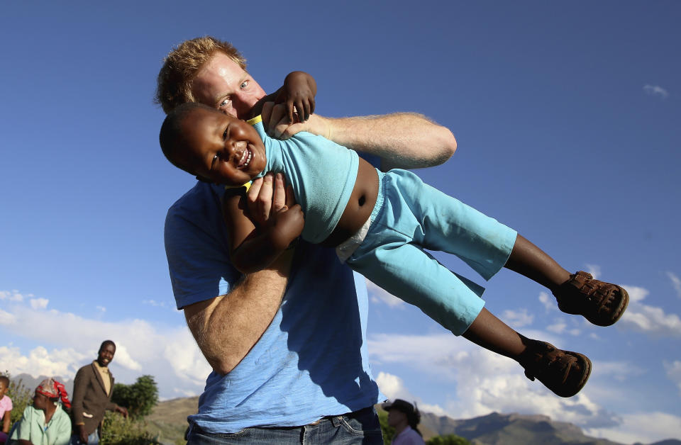 FILE - In this file photo taken on Dec. 6 2014, Britain's Prince Harry swings young three year old orphan boy Lerato in this photograph taken with the help of a three year old blind girl called Karabo during a visit to Phelisanong Children's Home in Maseru, Lesotho. Princess Diana’s little boy, the devil-may-care red-haired prince with the charming smile is about to become a father. The arrival of the first child for Prince Harry and his wife Meghan will complete the transformation of Harry from troubled teen to family man, from source of concern to source of national pride. (AP Photo / Chris Jackson, Pool, File)