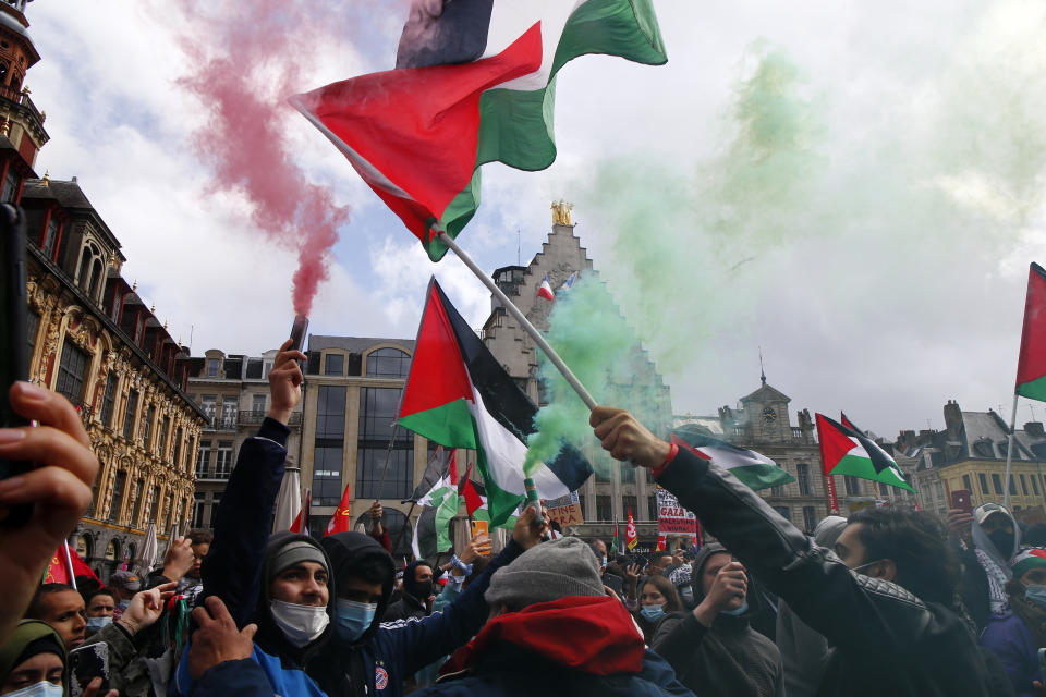 People hold Palestinian flags and flares during a demonstration in Lille, northern France, Saturday May 15, 2021. Marches in support of Palestinians in the Gaza Strip were being held Saturday in a dozen French cities, but the focus was on Paris, where riot police got ready as organizers said they would defy a ban on the protest. (AP Photo/Michel Spingler)