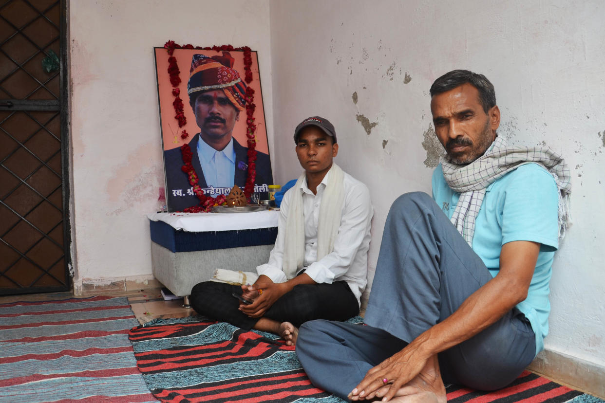 Yash Teli, left, next to his slain father’s photo with a relative at his home in Udaipur this month. (Yashraj Sharma)
