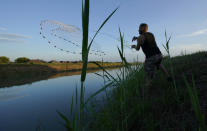 A man casts a net into a canal, Tuesday, Sept. 14, 2021, in McAllen, Texas. Canals used to deliver water in many parts of the Rio Grande Valley lose anywhere from 10% to 40% of the water they carry to seepage and evaporation, according to the Texas Water Development Board, making water a growing concern amid climate change and rising demand that scientists predict will lead to water shortages in the region by 2060.(AP Photo/Eric Gay)