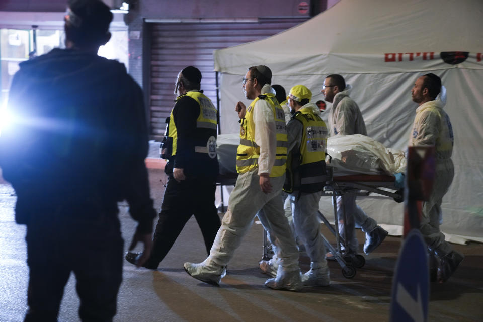 Israeli Zaka Rescue and Recovery team carry the body of a victim at the scene of shooting attack In Hadera, Israel, Sunday, March 27, 2022. A pair of gunmen killed two people and wounded four others in a shooting spree in central Israel before they were killed by police, according to police and medical officials. The identity of the gunmen was not immediately known, but police called them "terrorists," the term usually used for Arab assailants. (AP Photo/Ariel Schalit)