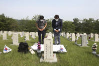 South Korean Park Tae-soon, left, and Park Young-soon wearing face masks to help protect against the spread of the new coronavirus pay their respects in front of the gravestone of their father Park Gong-jin who died during the Korean War, on Memorial Day at the national cemetery in Seoul, South Korea, Saturday, June 6, 2020. (AP Photo/Ahn Young-joon)
