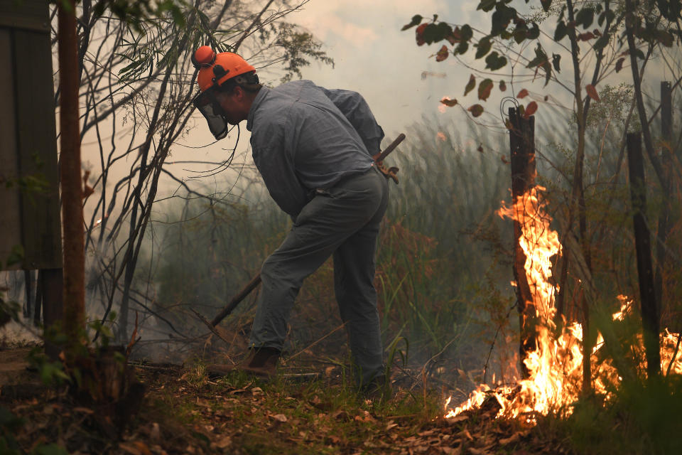Homeowner Rod Meggs puts out spot fires as NSW Rural Fire Service and Fire and Rescue NSW crews work to protect his property on Kyola Road in Kulnura as the Wrights Creek fire approaches Mangrove Mountain north of Sydney.