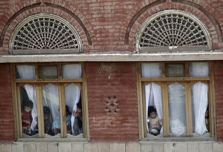 Children look from behind windows as supporters of the Shi'ite Houthi movement block a road as part of an anti-government protest in Sanaa September 3, 2014. REUTERS/ Khaled Abdullah