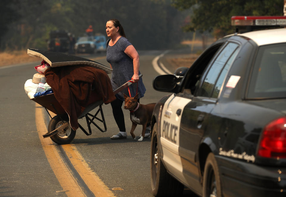 A resident pushes personal belongings in a wheelbarrow as she evacuates ahead of the River fire.