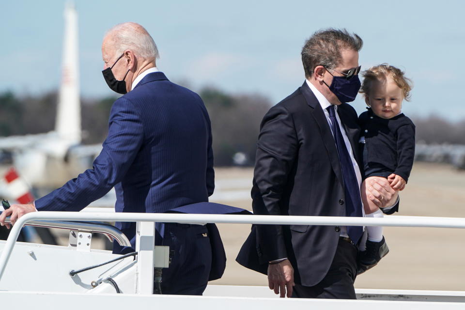 President Biden on a walkway on a plane with his son Hunter, in a mask, carrying Beau.