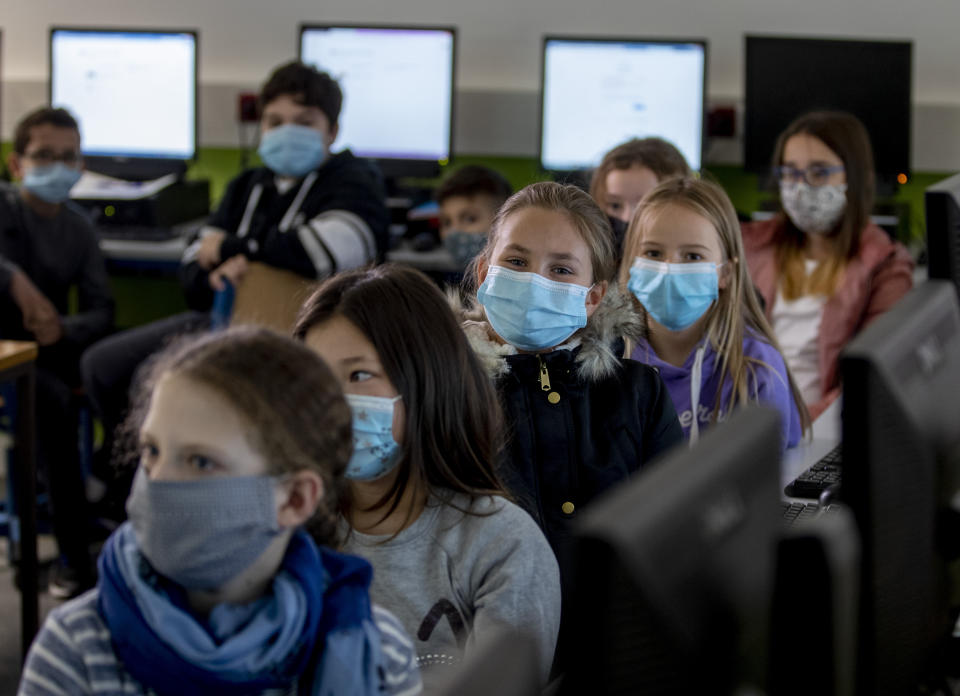 FILE - In this Oct. 21, 2020 file photo, pupils of a fifth class at a high school wear face masks as they take part in an electronic learning session in Frankfurt, Germany. More than 50,000 people have died after contracting COVID-19 in Germany, a number that has risen swiftly over recent weeks as the country has struggled to bring down infection figures. (AP Photo/Michael Probst, File)