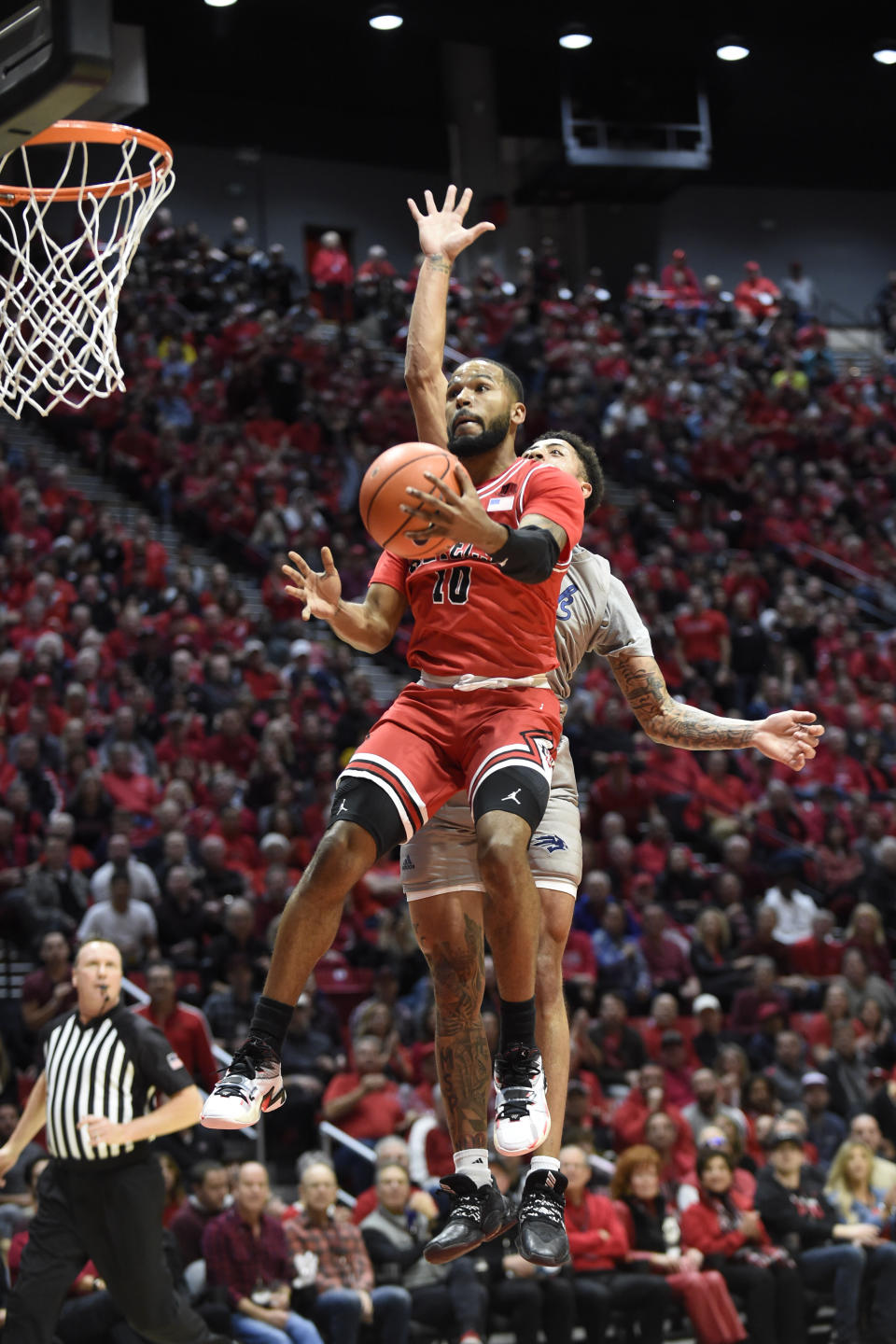 San Diego State guard KJ Feagin (10) shoots past the defense of Nevada guard Jalen Harris during the first half of an NCAA college basketball game Saturday, Jan. 18, 2020, in San Diego. (AP Photo/Denis Poroy)