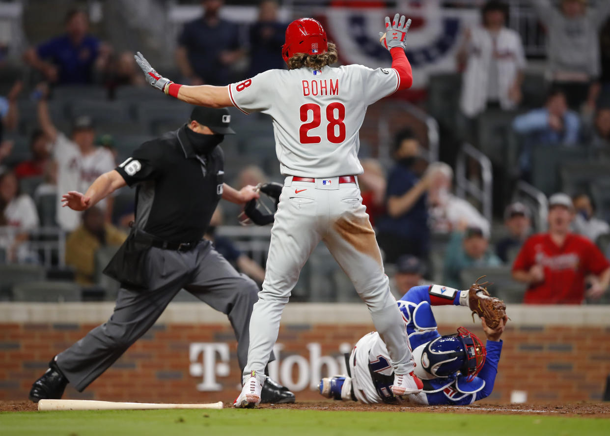 Alec Bohm of the Philadelphia Phillies slides and beats the tag of Travis d'Arnaud of the Atlanta Braves