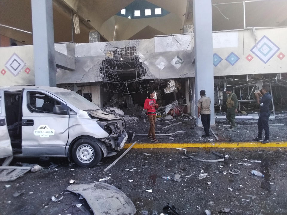 Bystanders and a soldier stand near a damaged portion of the airport of Yemen’s southern city of Aden’s after an explosion, Wednesday, Dec. 30, 2020. The blast struck the airport building shortly after a plane carrying the newly formed Cabinet landed on Wednesday. No one on the government plane was hurt. (AP Photo/Majid Saleh)