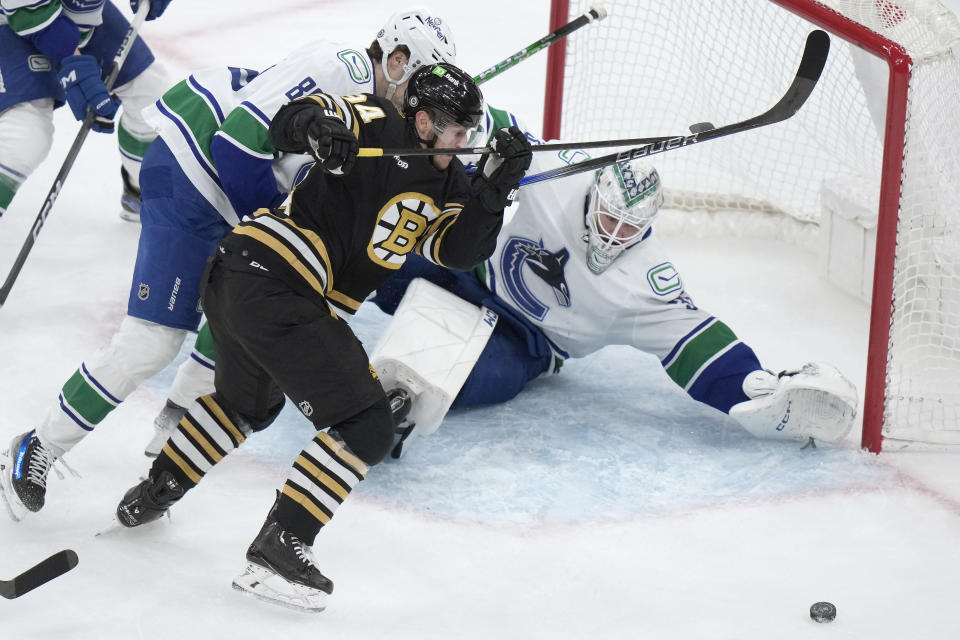 Boston Bruins center Jakub Lauko, front left, is unable to score as Vancouver Canucks goaltender Thatcher Demko, right, deflects the puck during the first period of an NHL hockey game Thursday, Feb. 8, 2024, in Boston. (AP Photo/Steven Senne)