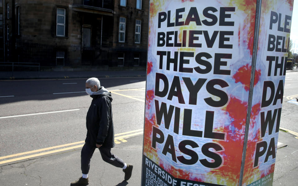 A person walks passed a billboard poster outside Glasgow Royal Infirmary as the UK continues in lockdown to help curb the spread of the coronavirus.