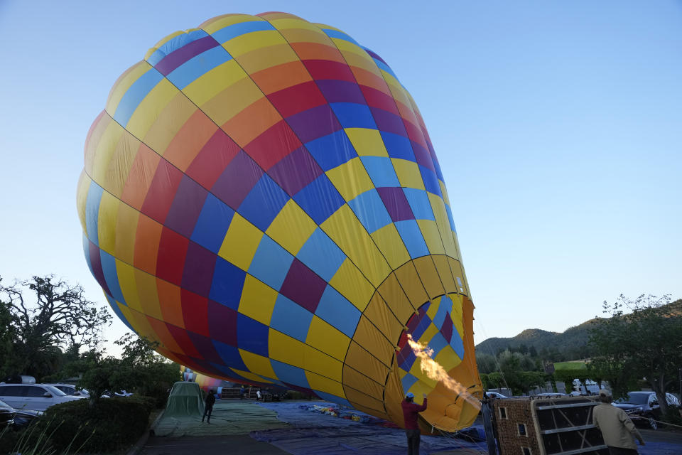 A Napa Valley Aloft balloon is inflated with hot air before lifting off in Yountville, Calif., Monday, June 19, 2023. This year, wine grapes are thriving after a winter of record amounts of rain fell in California, but a recent trip high above the valley in a hot air balloon revealed miles of lush, green vineyards — the only blemish coming from shadows cast by the balloons themselves. (AP Photo/Eric Risberg)