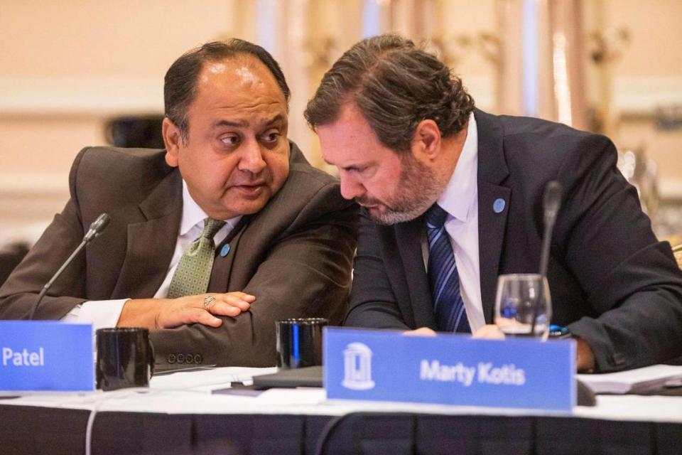 Vinay Patel, left, whispers to Marty Kotis during their first meeting as a members of the UNC Board of Trustees, at the Carolina Inn, on Thursday, July 15, 2021, in Chapel Hill, N.C.