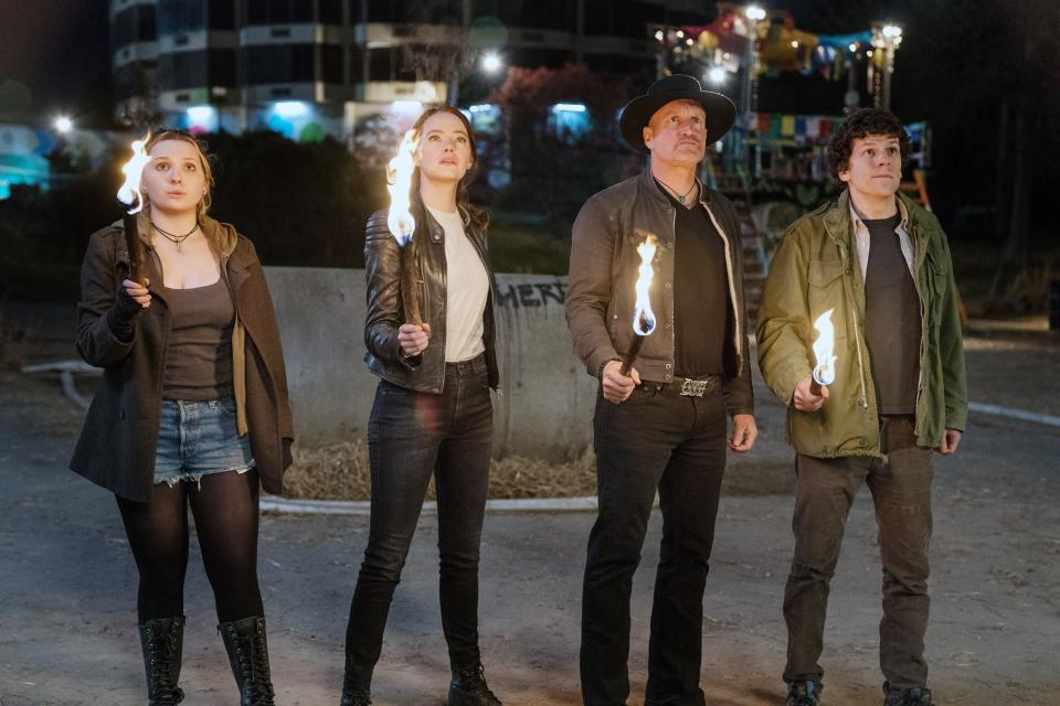 Abigail Breslin, Emma Stone, Woody Harrelson, and Jesse Eisenberg hold torches