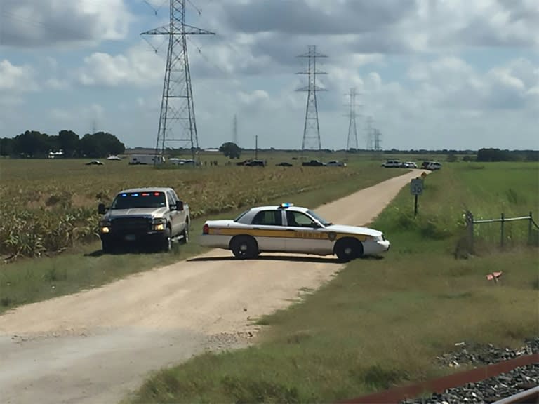 This handout photograph obtained courtesy of KXAN TV shows a police vehicle blocking a road where a hot air balloon crashed near Lockhart, Texas, July 30, 2016