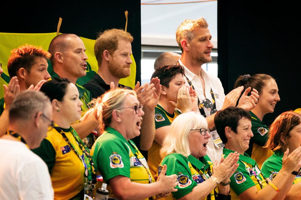 Prince Harry is shown clapping cheering at the Invictus Games with fans of Team Australia.