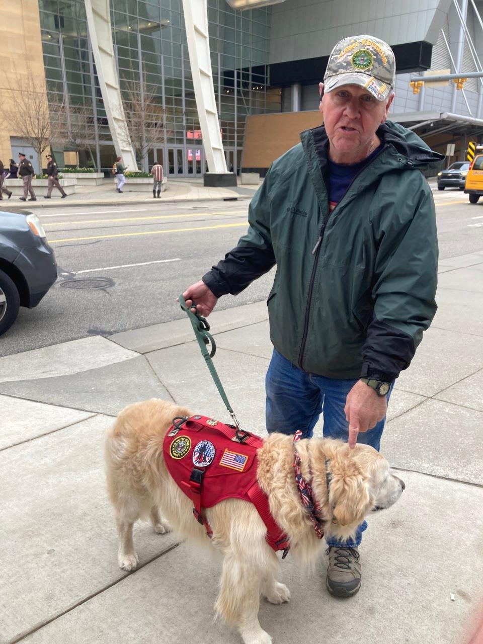 Steve Kenyon of Grand Rapids, shown here with his therapy dog "Scout," demonstrated outside the DeVos Place Convention Center in favor of former President Donald Trump on Tuesday, April 2, 2024.