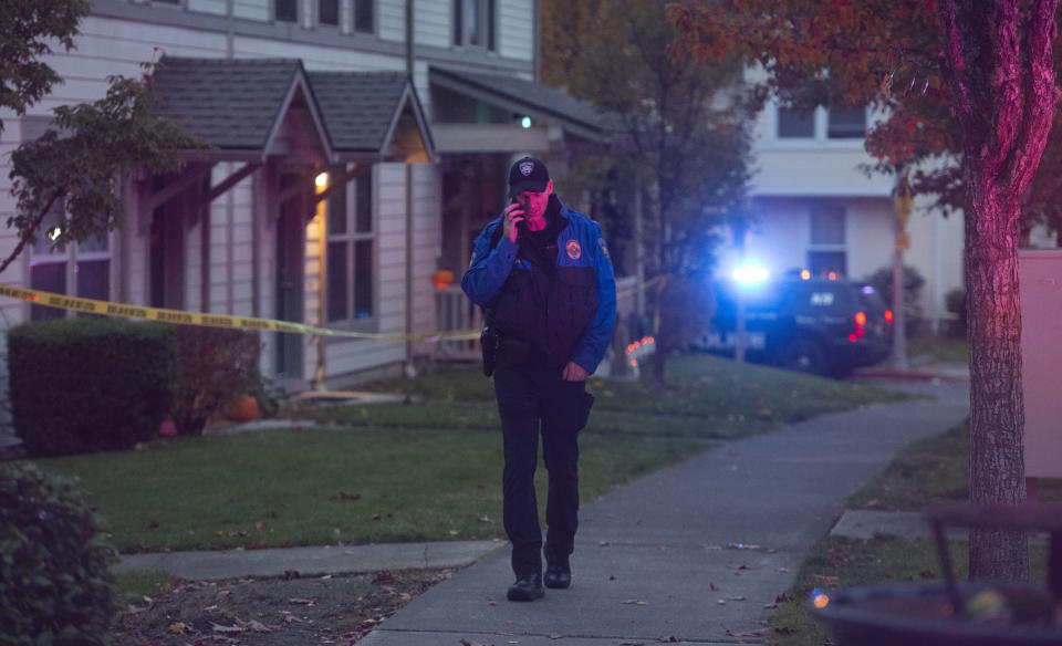 A Tacoma police officer takes a call near the scene of a shooting in Tacoma, Wash. Thursday, Oct. 21, 2021. Four people were killed in a shooting in Tacoma on Thursday afternoon, police said. (Drew Perine/The News Tribune via AP)