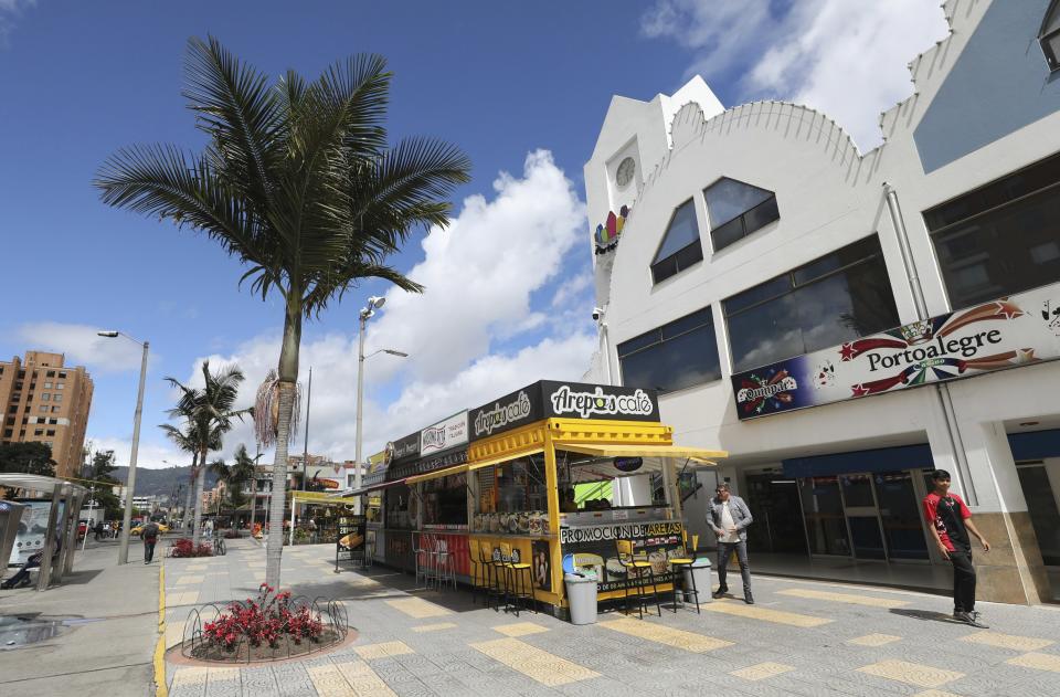 In this June 11, 2019 photo, Gerson Briceno, second right, owner of the fast food restaurant "Arepas Cafe" waits for customers in Bogota, Colombia, Tuesday, June 11, 2019. Briceno first started a cell phone business, but opened an arepa stand outside a mall in December 2017 when he found himself wanting to pay tribute to his cherished homeland. (AP Photo/Fernando Vergara)