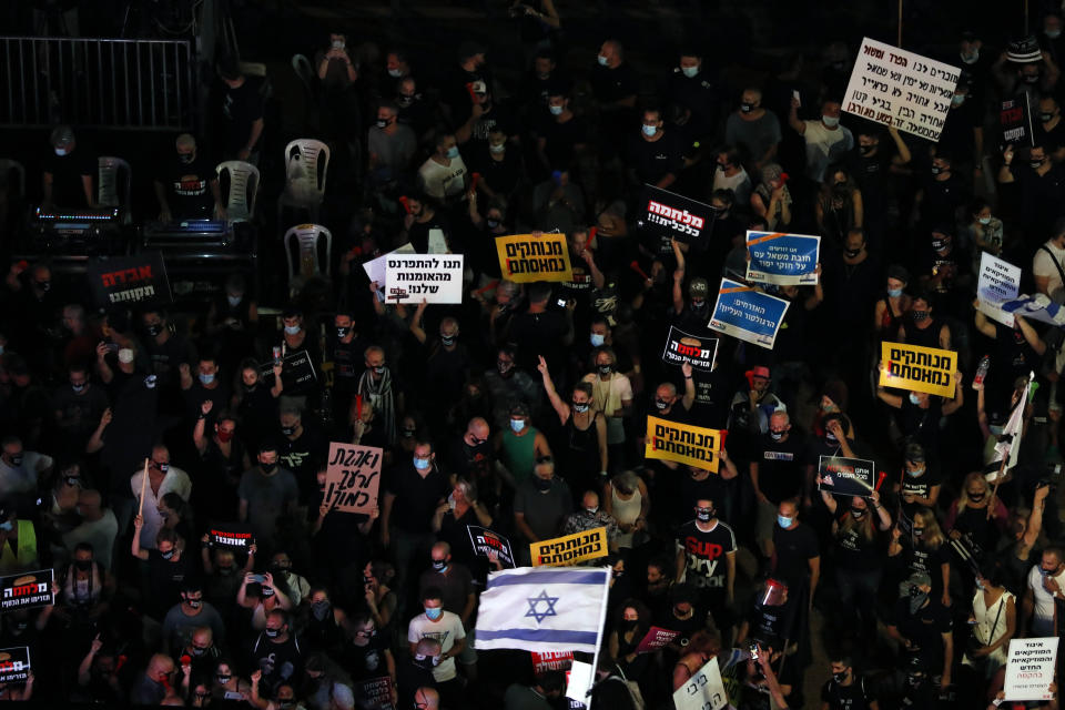 Protesters hold signs during a demonstration against Israel's government in Rabin square in Tel Aviv, Israel, Saturday, July 11, 2020. Thousands of Israelis gathered Saturday to protest the new government's failure to address economic woes brought by the coronavirus, directing their anger at Prime Minister Benjamin Netanyahu who is seeing his support plummeting. (AP Photo/Ariel Schalit)