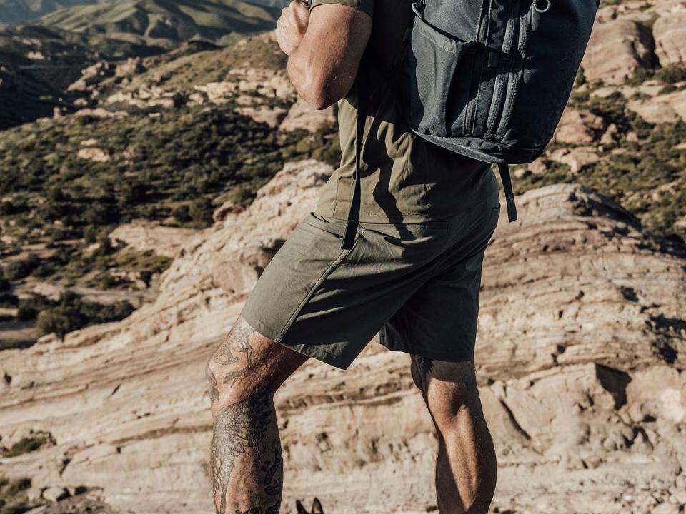 an athlete wearing a part of fitness shorts and a backpack while hiking a mountainous terrain