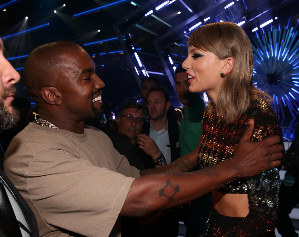 kanye grabbing taylor's shoulders as the two talk at a show