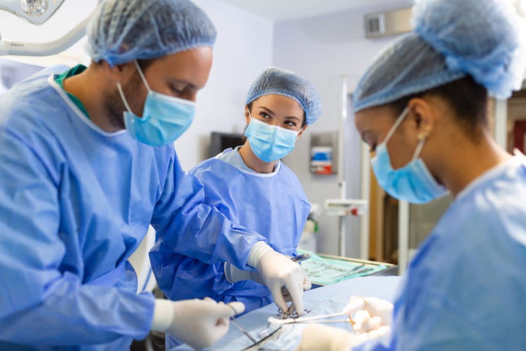 People perform surgery in an operating room. 