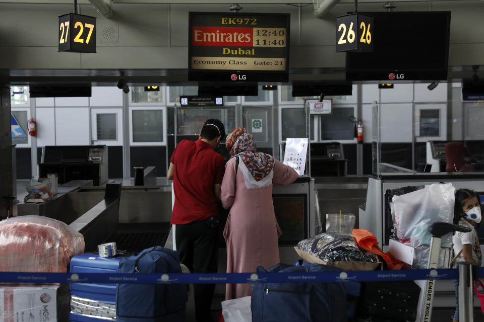 Passengers fill out a health declaration form as they check in at the Emirates airliner counter at Tehran's Imam Khomeini airport, Iran, Friday, July 17, 2020. The first Emirates flight arrived in Iran after nearly 5 months of suspension of the most airliners flights to the country due to the coronavirus outbreak, as Iranian officials at the airport say they are doing everything possible to ensure passengers are not infected, and isolate those with symptoms. (AP Photo/Vahid Salemi)