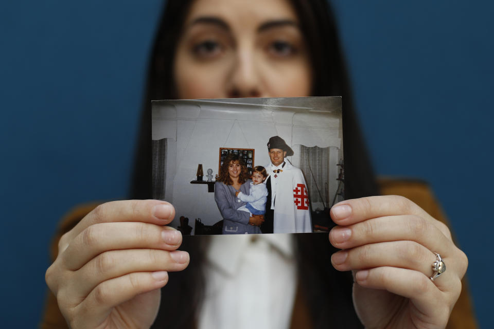 Mary Rose Maher, the daughter of Opus Bono Sacerdotii co-founder Joe Maher, holds a photo of her as a child with her parents in Detroit, Wednesday, June 12, 2019. Opus Bono's finances came under scrutiny after authorities were contacted by a once-loyal employee - Mary Rose - who began questioning the way money was spent. (AP Photo/Paul Sancya)