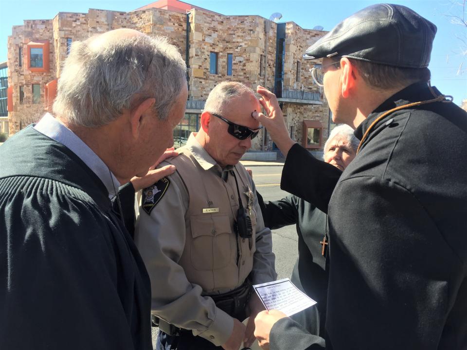 Doña Ana County Sheriff's Office deputy Robbie Acosta gets ashes on his forehead by Rev. Wally LaLone and other members of St. Andrew's Episcopal Church on University Avenue, during the church's "Ashes to Go" service on Ash Wednesday. The church performed ash services along University Avenue near Espina Street for those who could not attend services at a church around town.