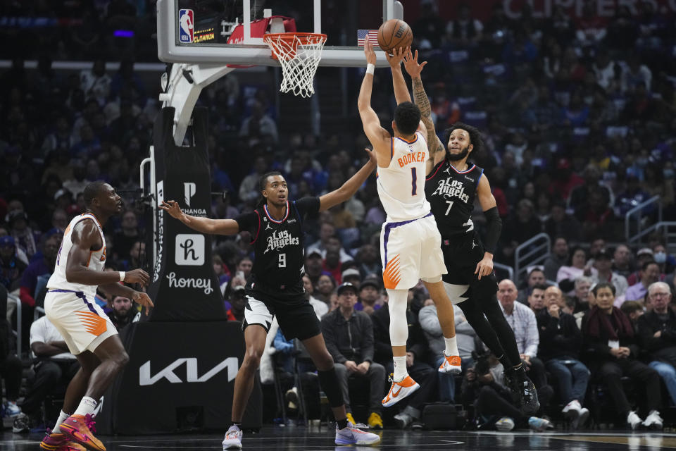 Phoenix Suns guard Devin Booker (1) shoots against LA Clippers center Moses Brown (9) and guard Amir Coffey (7) during the first half of an NBA basketball game in Los Angeles, Thursday, Dec. 15, 2022. (AP Photo/Ashley Landis)