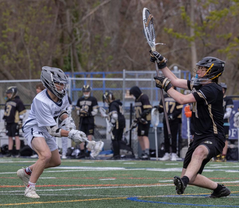 Manasquan's Brandon Kunz (No. 12) shoots low as Point Boro's Matthew Azzarano (No. 44) tries to block his shot. Manasquan Boys Lacrosse defeats Point Pleasant Boro in Manasquan, NJ on April 27, 2022.