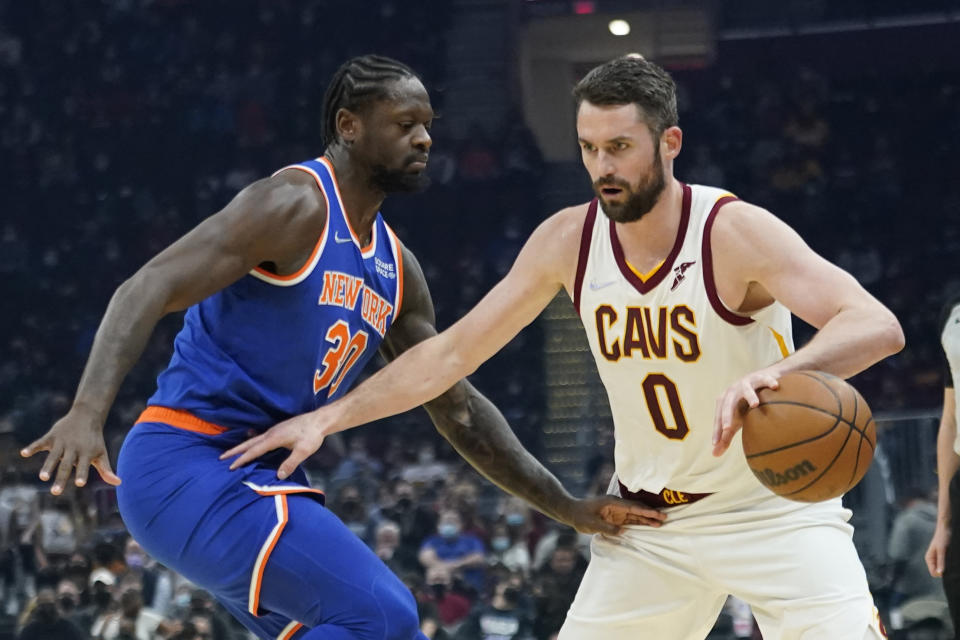 Kevin Love (0) de los Cleveland Cavaliers bota el balón ente el jugador de los New York Knicks Julius Randle (30) en la primera mitad de un juego de la NBA, el lunes 24 de enero de 2022, en Cleveland. (AP Foto/Tony Dejak)