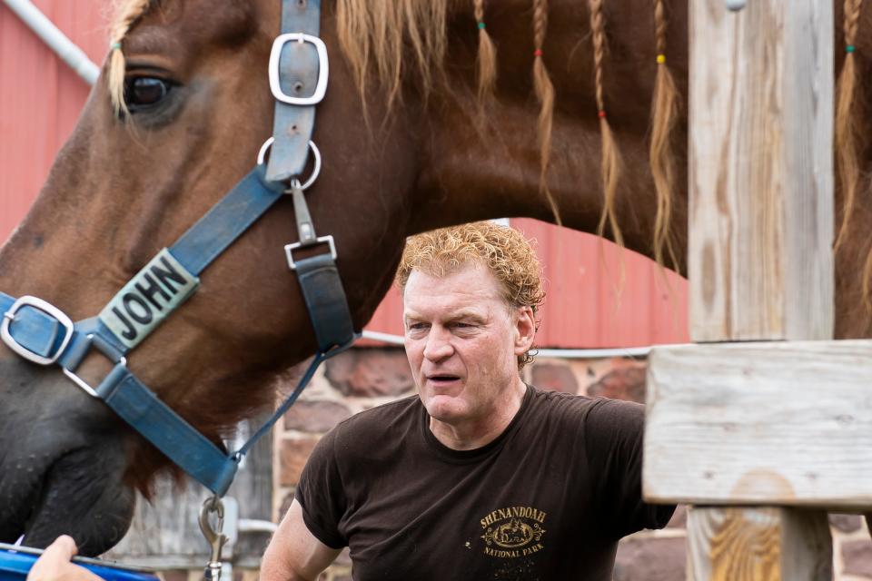 Farrier Drew Myers and "Big John," an 1,800-pound draft horse, both take a break during a hoof cleaning session at Central Pa Horse Rescue on June 24, 2022. Big John lived out his final five years at the rescue and died later last summer.