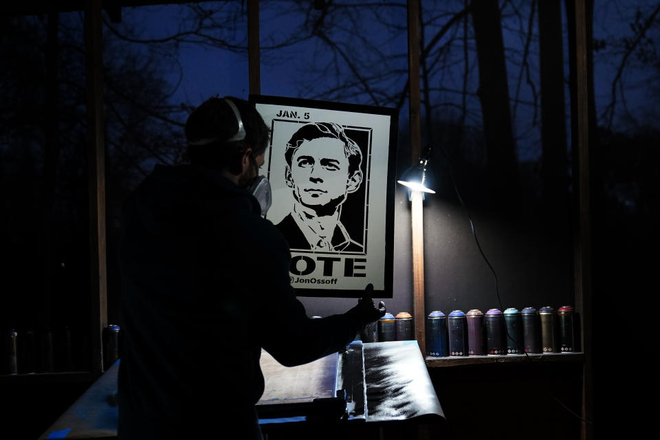 Artist Brandon Litman holds up a U.S. Senator-elect Jon Ossoff, D-Ga., campaign poster after spray painting it after Georgia's Senate runoff race on Saturday, Jan. 9, 2021, in Atlanta. (AP Photo/Brynn Anderson)