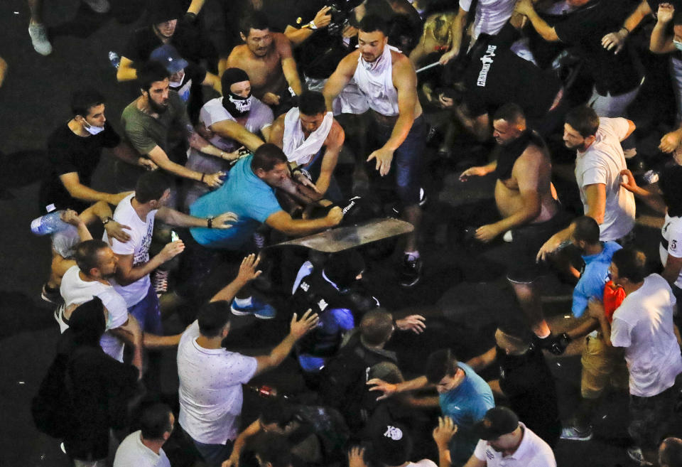 People mob riot police officers who fell and were left behind during a charge to clear the square during protests outside the government headquarters, in Bucharest, Romania, Friday, Aug. 10, 2018. Romanians who live abroad are staging an anti-government protest calling on the left-wing government to resign and an early election.(AP Photo/Vadim Ghirda)