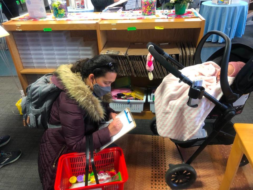 Marissa Campbell, a kindergarten teacher at Creech Road Elementary School, shops for free classroom supplies at the grand opening of WakeEd Partnership’s Tools4Schools store in Cary, N.C., on Jan. 18, 2022. She’s accompanied by her 7-month-old daughter.