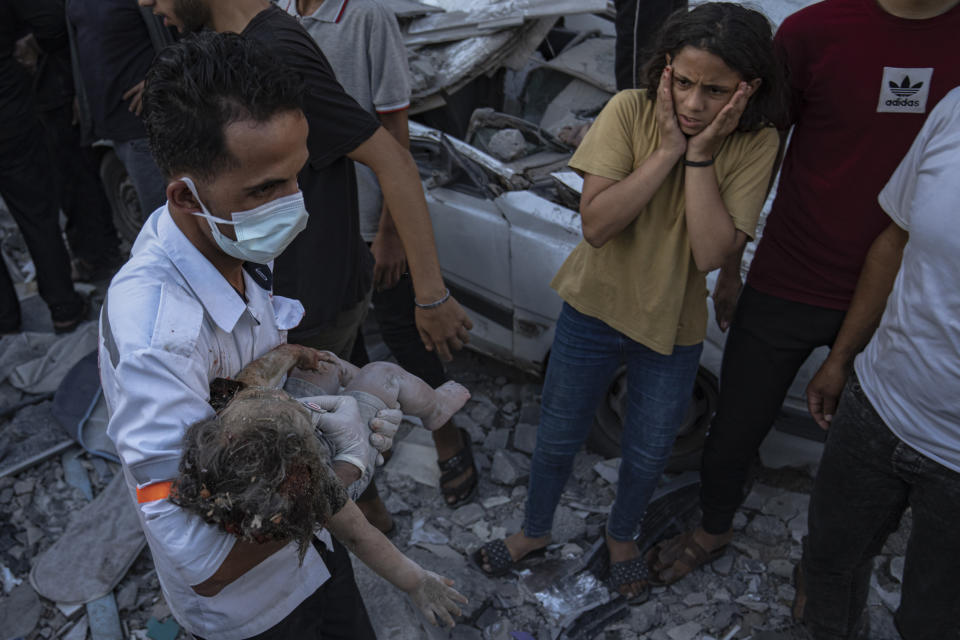 A Palestinian reacts as a child is carried from the rubble of a building after an airstrike in Khan Younis, Gaza Strip, Saturday, Oct. 21, 2023. (AP Photo/Fatima Shbair)