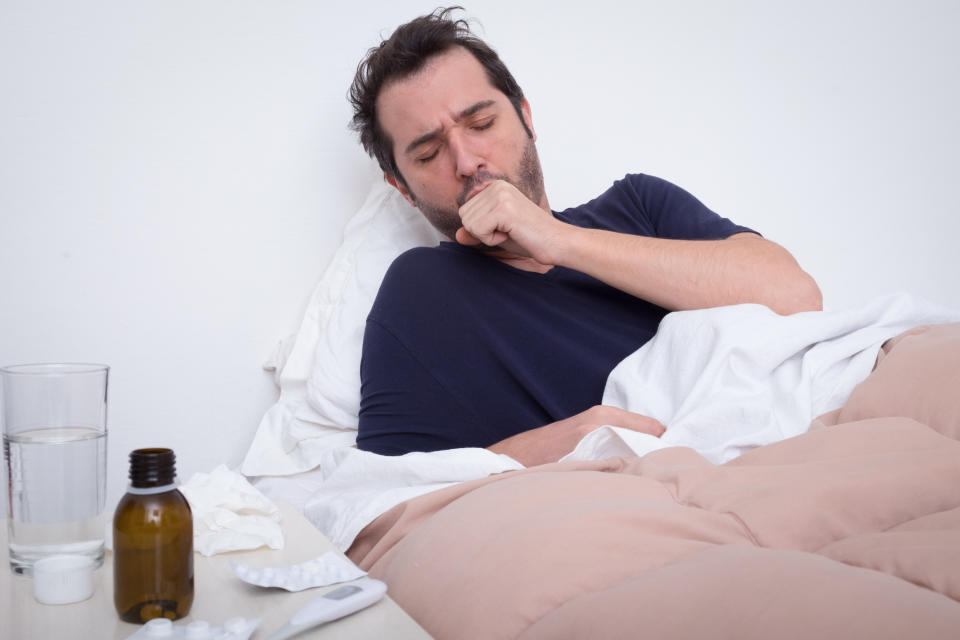 Man lying in bed, coughing.