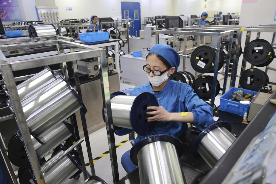 In this Aug. 14, 2019, photo, a woman works on a production line in a fiber optics factory in Nantong in eastern China's Jiangsu province. U.S. President Donald Trump angrily escalated his trade fight with China on Friday, Aug. 23, 2019, raising retaliatory tariffs and ordering American companies to consider alternatives to doing business there. (Chinatopix via AP)